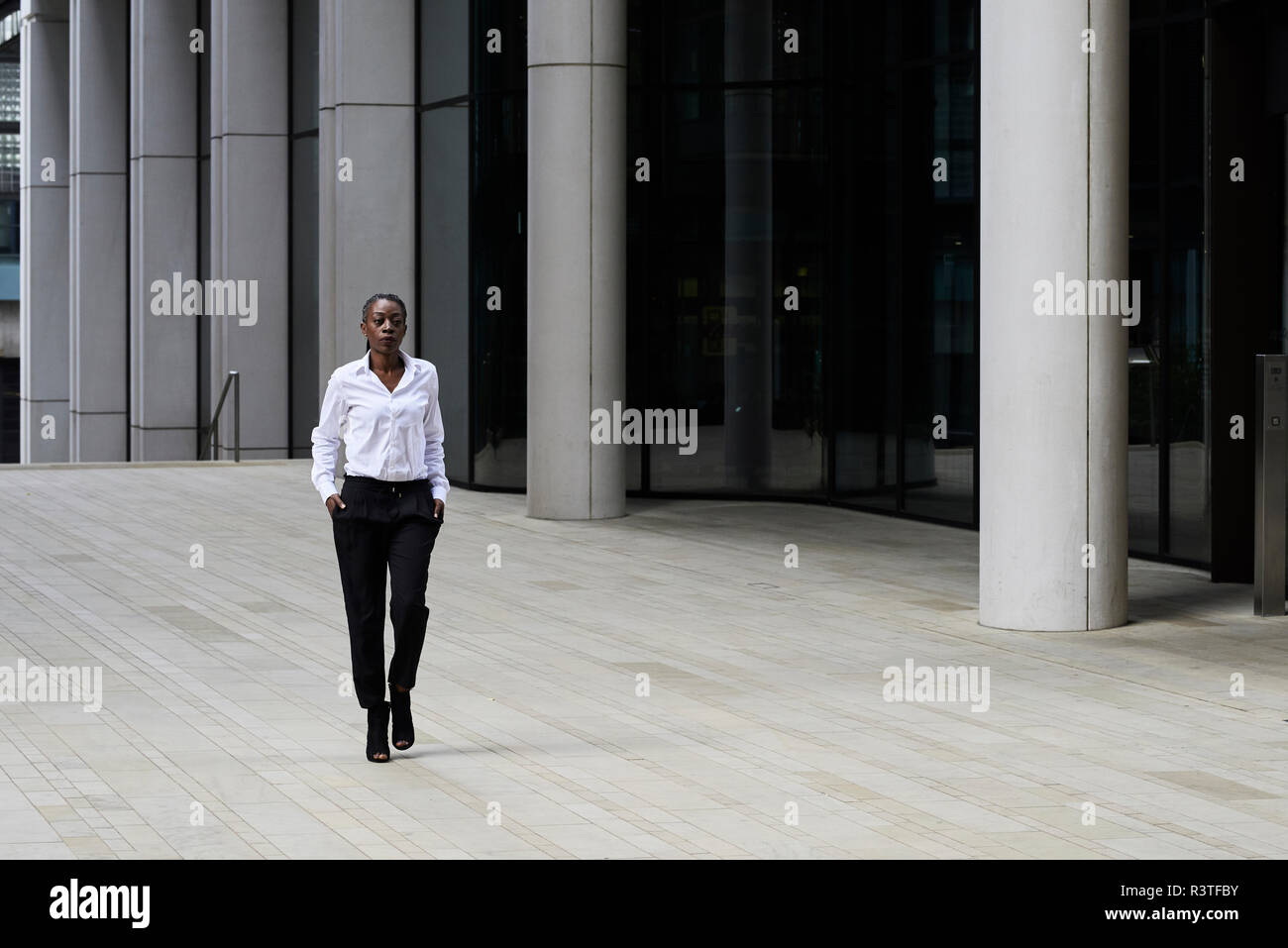 Geschäftsfrau, tragen weiße Hemd und schwarzen Hosen vor ein modernes Bürogebäude Stockfoto