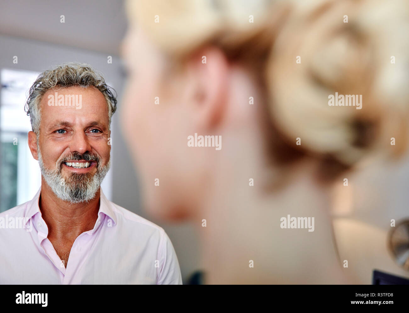 Lächelnd reifer Mann bei weiblichen Kollegen suchen Stockfoto