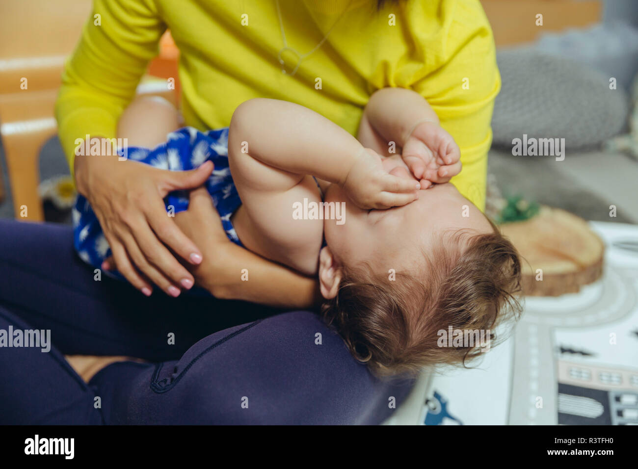 Müde, Baby Mädchen Augen reiben auf dem Schoß der Mutter Stockfoto