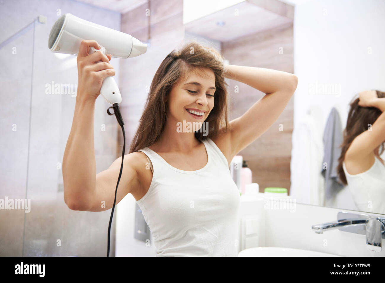 Portrait von lachende Frau mit Fön im Badezimmer Stockfoto