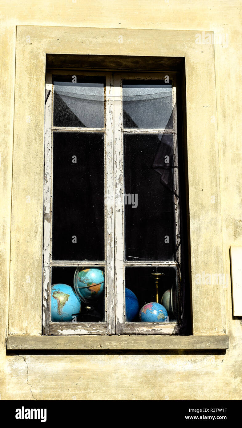 Eine Fülle von Globen können durch die Bröckelnden Windows einer alten Regierung Bürogebäude in Villafranca in Lunigiana, Toskana, Italien flüchtig gesehen werden. Stockfoto