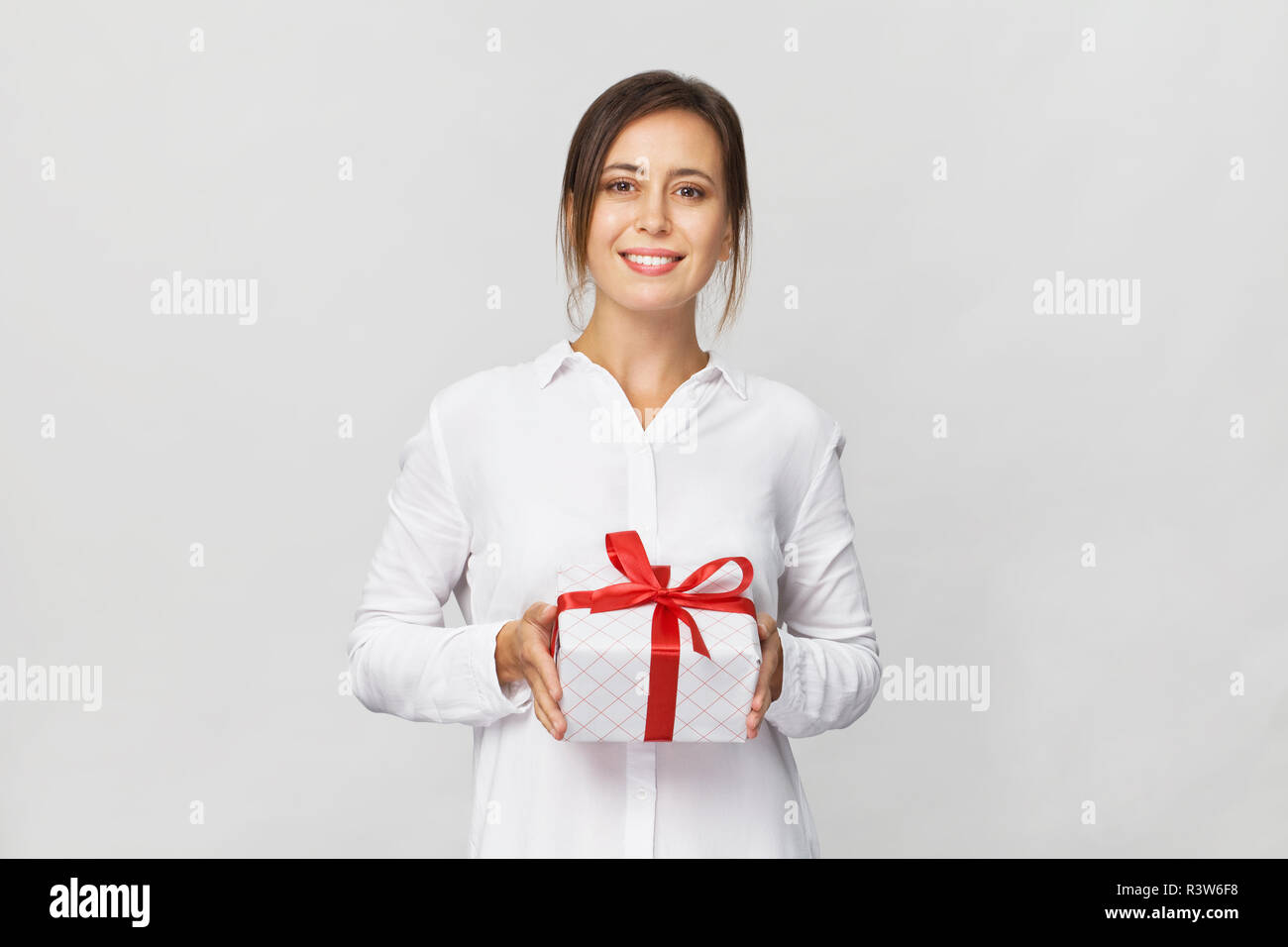 Glückliche junge geschäftsfrau mit einer Geschenkbox, red ribbon auf weißem Hintergrund. Stockfoto