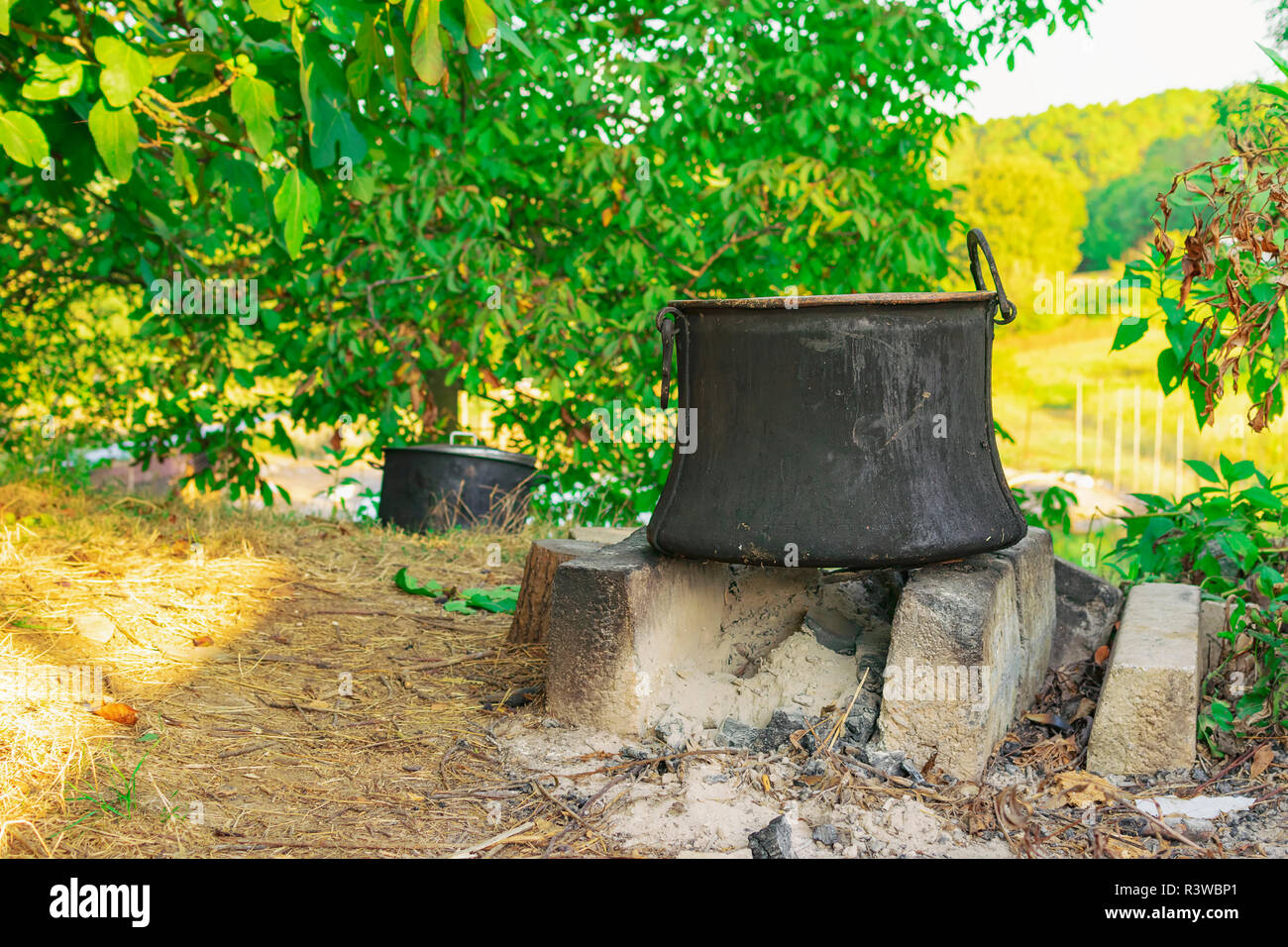 Alte Kupfer Topf zum Kochen stehen auf Beton Ziegel auf Kamin im Hinterhof Stockfoto