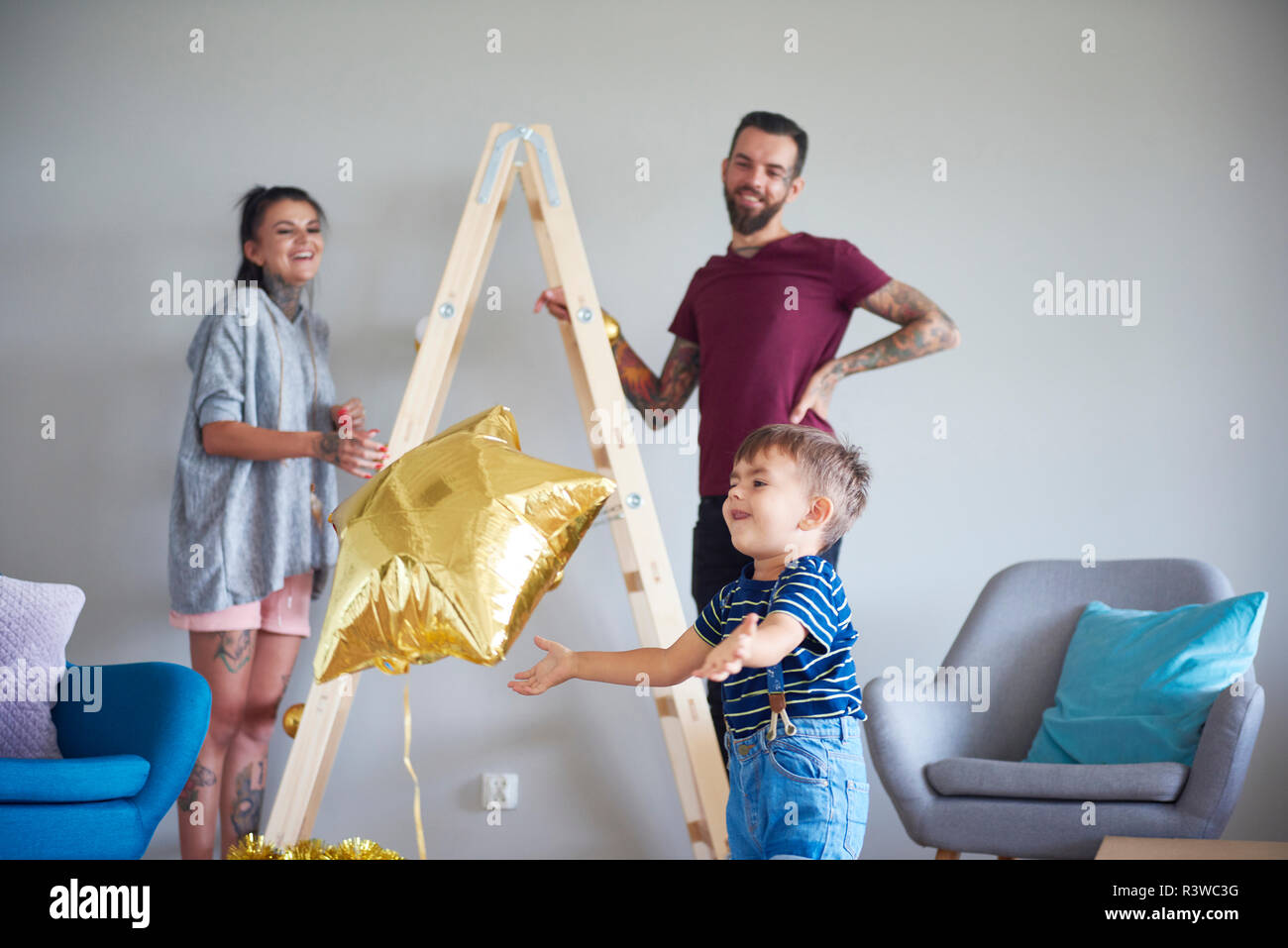 Moderne Familie dekorieren zu Hause an Weihnachten mit Leiter als Weihnachtsbaum Stockfoto