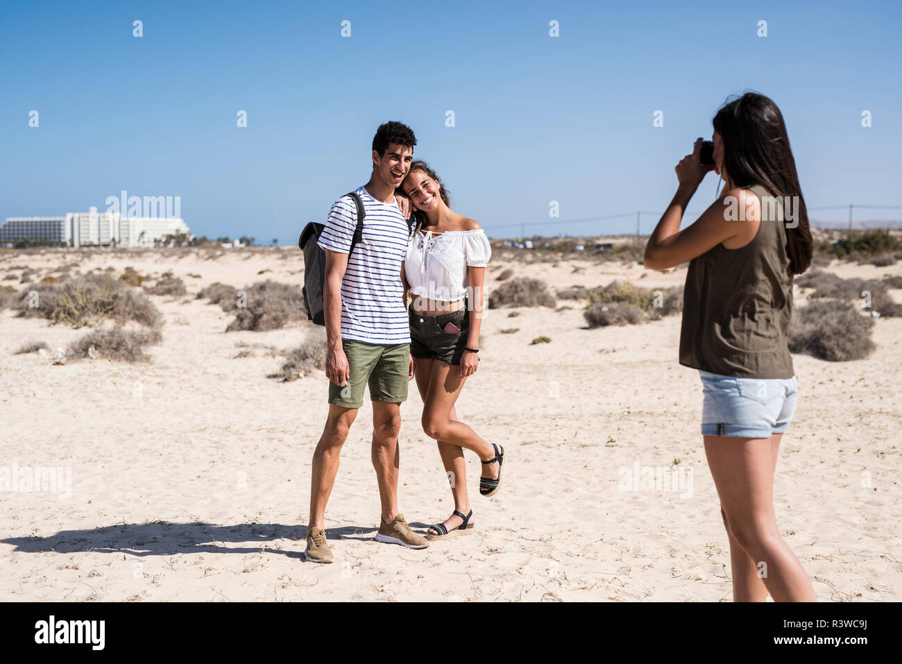 Junge Frau, die Bilder von einem jungen Paar am Strand Stockfoto