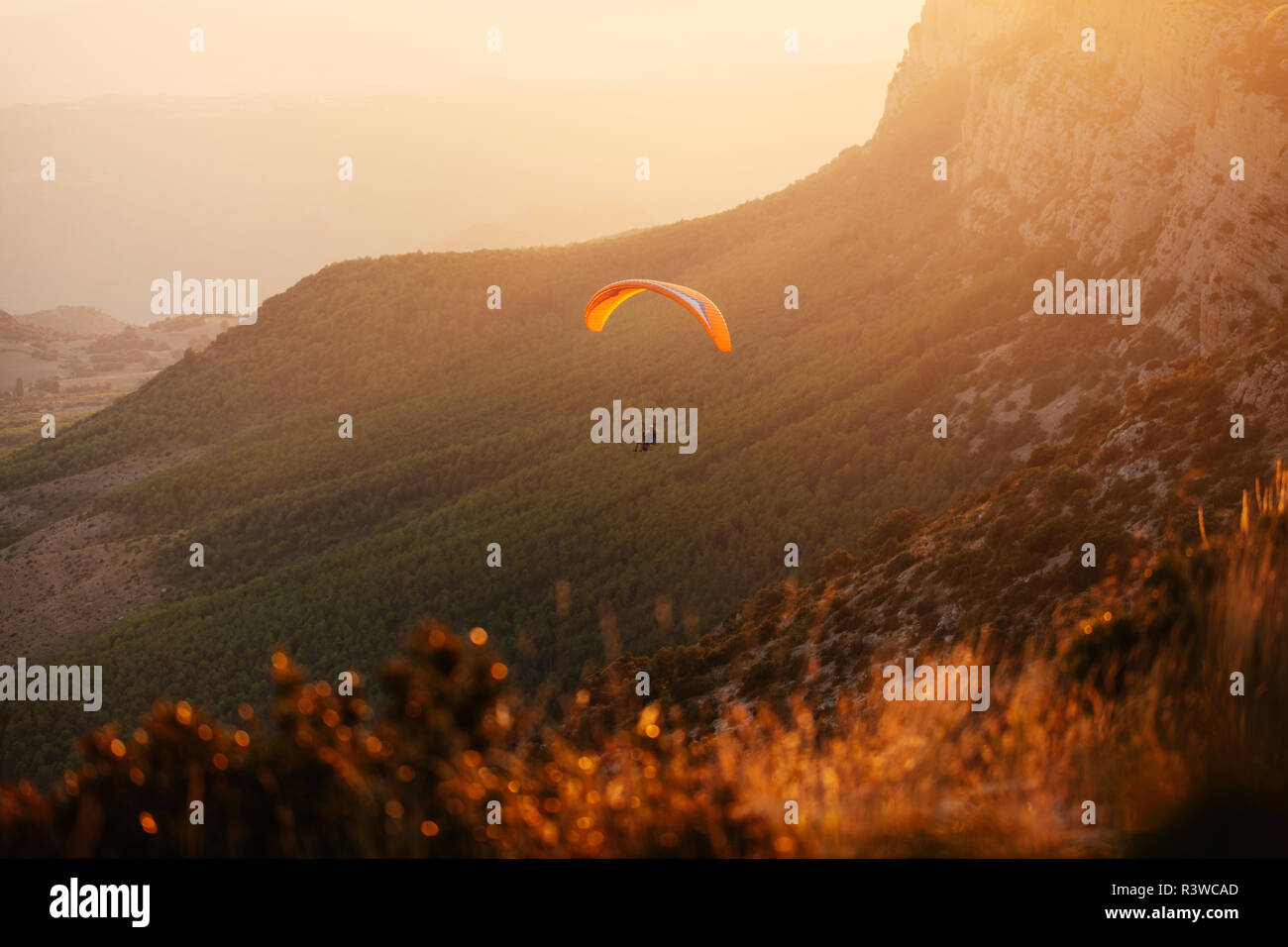 Spanien, Silhouette von Gleitschirm soaring hoch über die Berge bei Sonnenuntergang Stockfoto