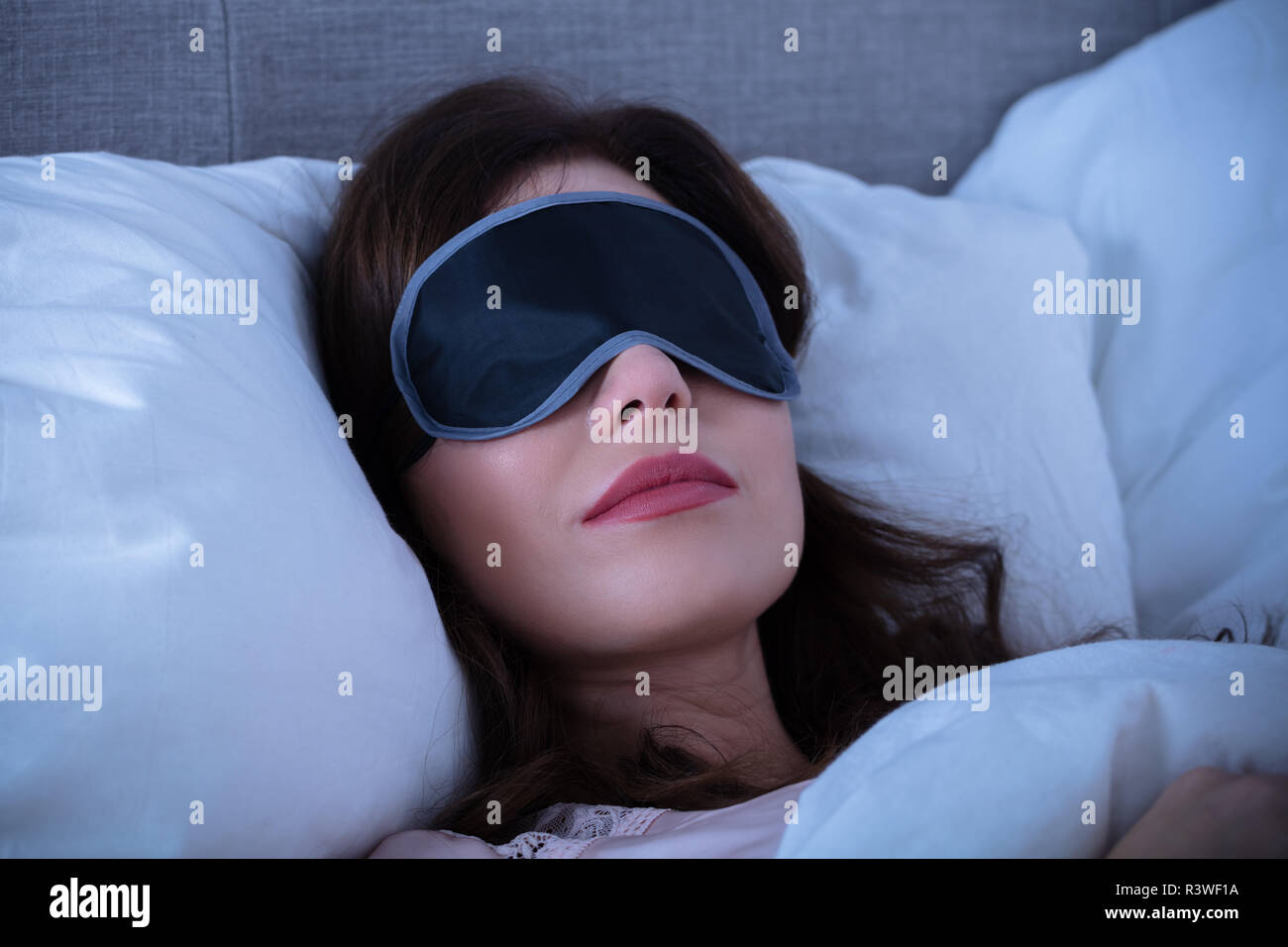 In der Nähe der schöne junge Frau schlafen auf Bett mit Augenmaske Stockfoto