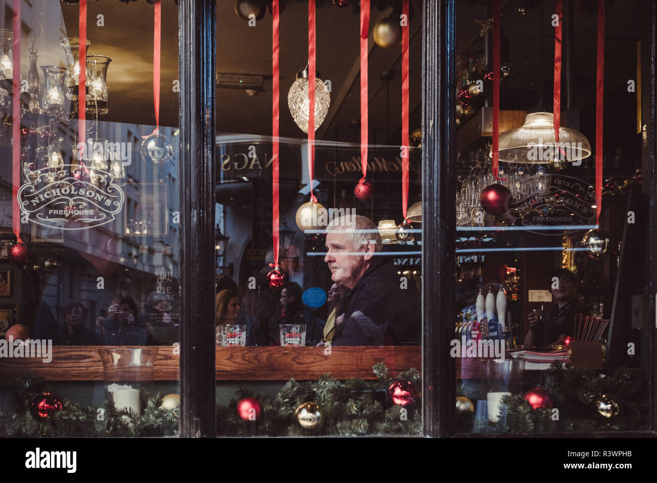 London, Großbritannien, 7. Dezember 2017. Ein Mann in Covent Garden Pub an der Massen von Weihnachtskäufer suchen, gesehen durch das Fenster Stockfoto