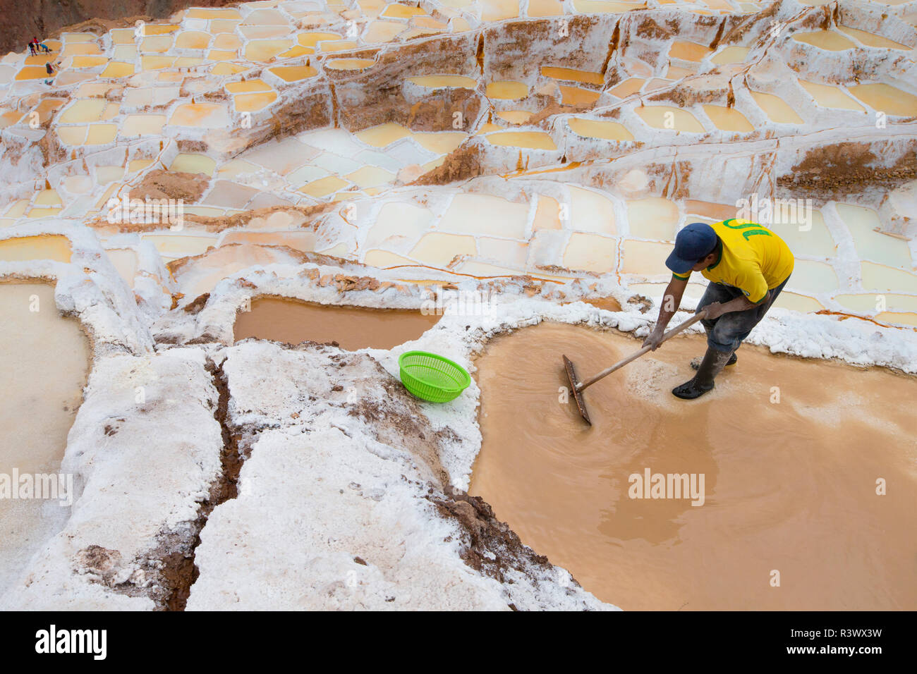 Bezirk Cusco, Peru. Mann bei der Arbeit die Maras Salzbergwerk Verdunstung Pools. Stockfoto