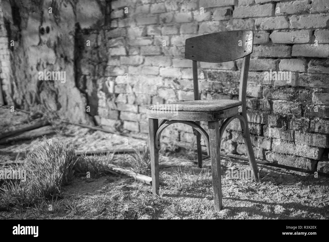 Alten hölzernen Stuhl stehend in der Nähe der Wand eines zerstörten Hauses Stockfoto