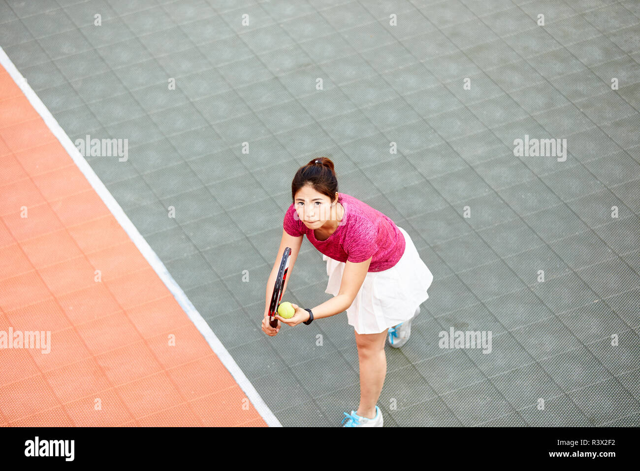 Junge asiatische Frau tennis player bereit zu dienen Stockfoto