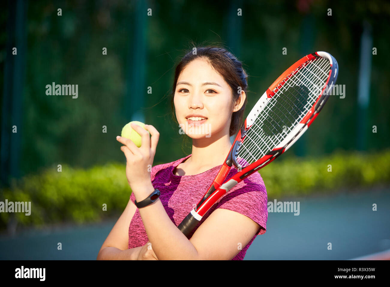 Outdoor portrait einer jungen asiatischen Tennisspieler an der Kamera schaut lächelnd Stockfoto