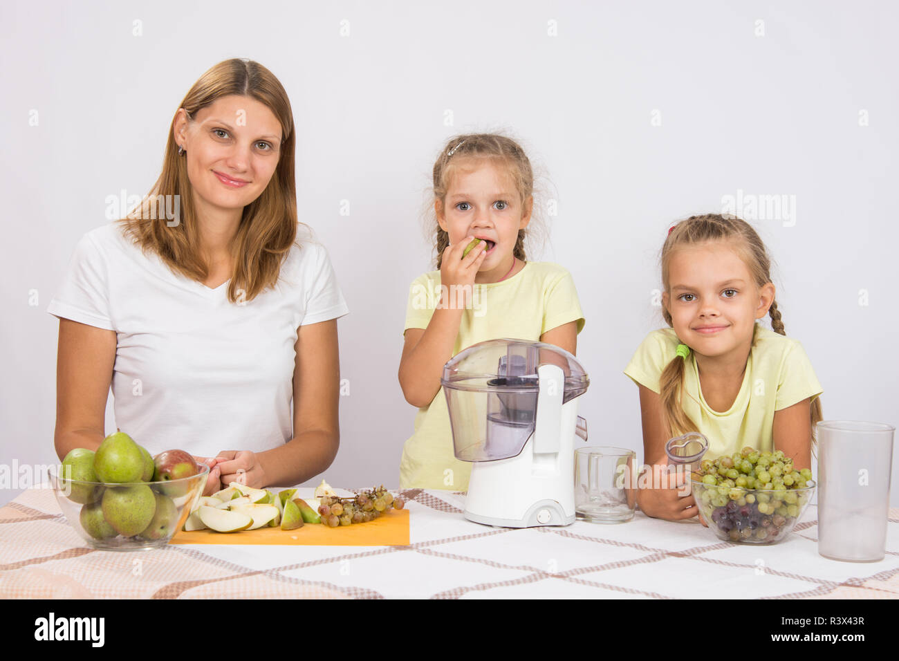 Mutter und Tochter sitzen am Tisch mit einem Entsafter und Obst Stockfoto
