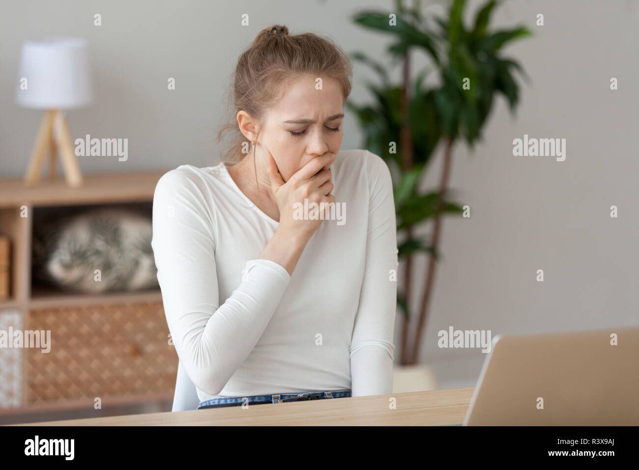 Müde weibliche Seufzer am Laptop zu Hause arbeiten Stockfoto