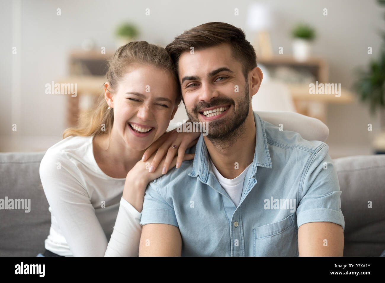 Portrait von Happy tausendjährigen Paar Hug auf der Couch zu Hause Stockfoto