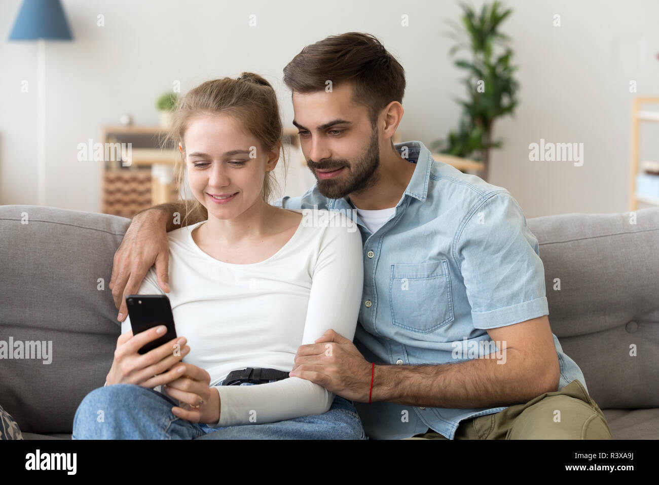 Glückliches Paar auf der Couch Ansehen von Videos auf dem Smartphone Entspannen Stockfoto