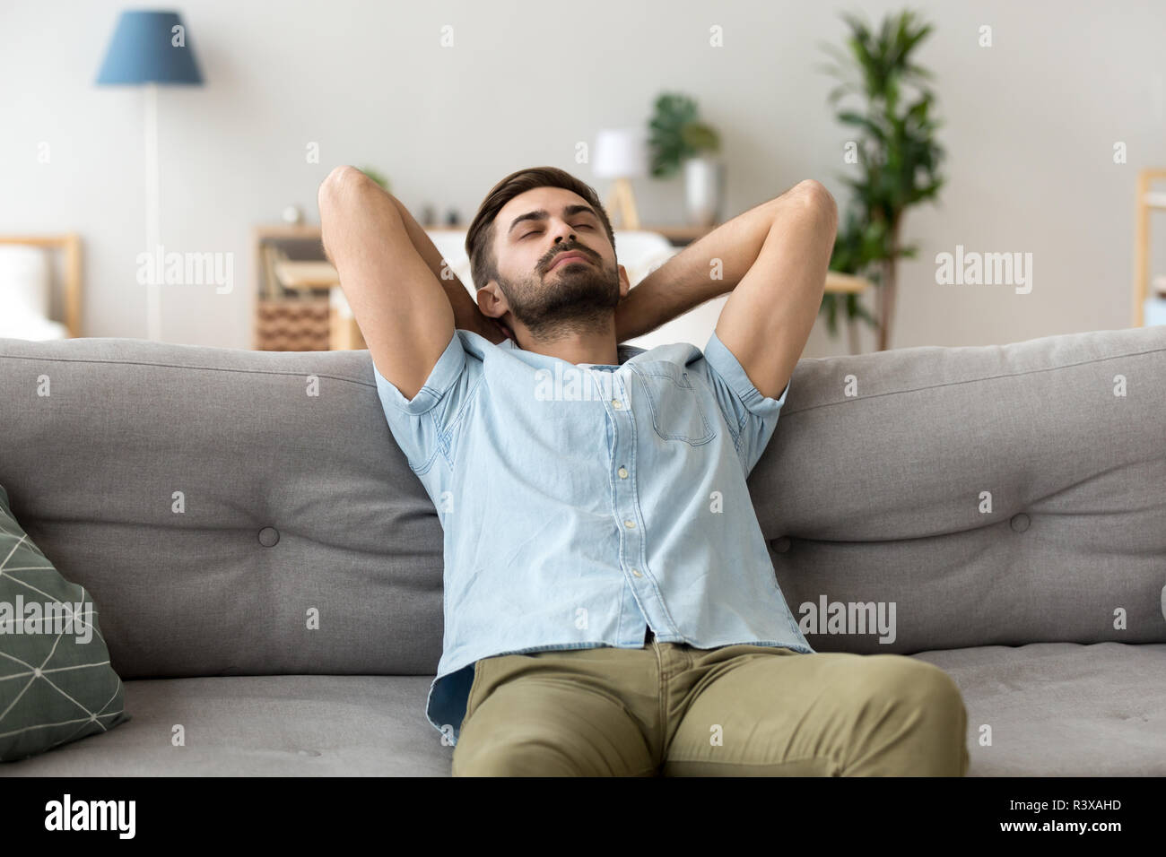 Ruhigen Menschen entspannen auf dem Sofa die Hände über dem Kopf Stockfoto