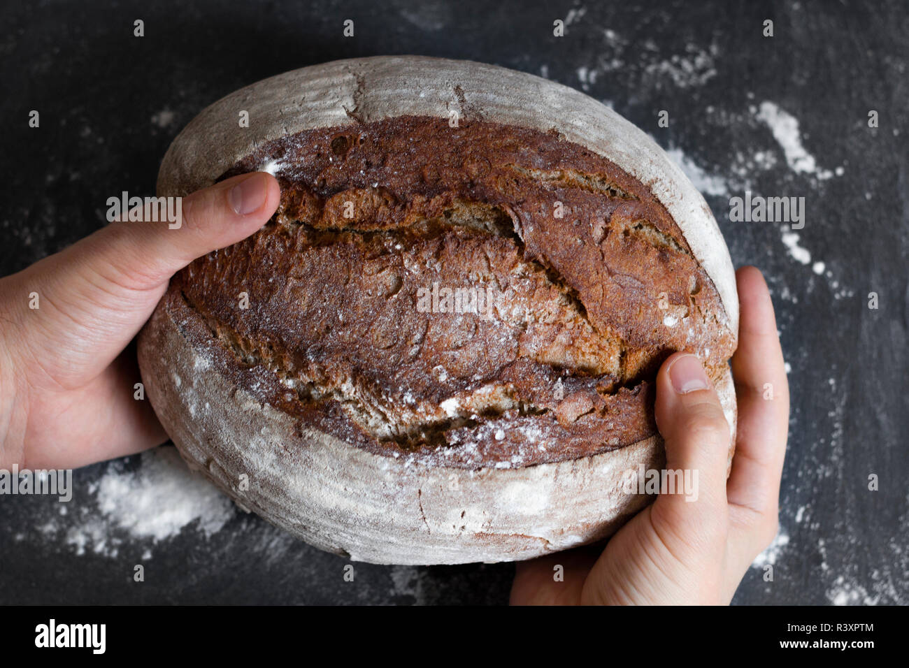 Männliche Hände, die ganzen Brotlaib Stockfoto