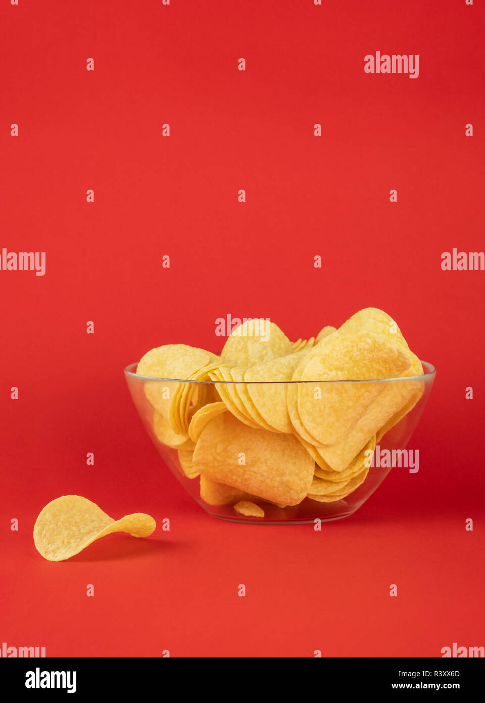 Schüssel Chips in hellen roten Hintergrund. Minimalistischer Bild von Aufmerksamkeitsstarke fast food in lebendigen Farben Stockfoto