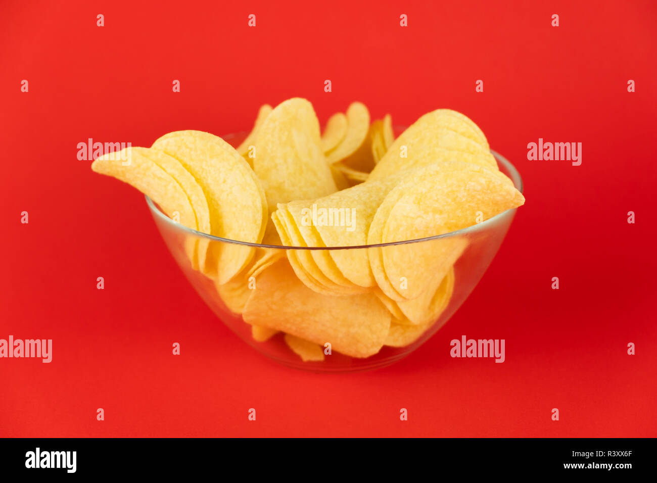 Schüssel Chips in hellen roten Hintergrund. Minimalistischer Bild von Aufmerksamkeitsstarke fast food in lebendigen Farben Stockfoto