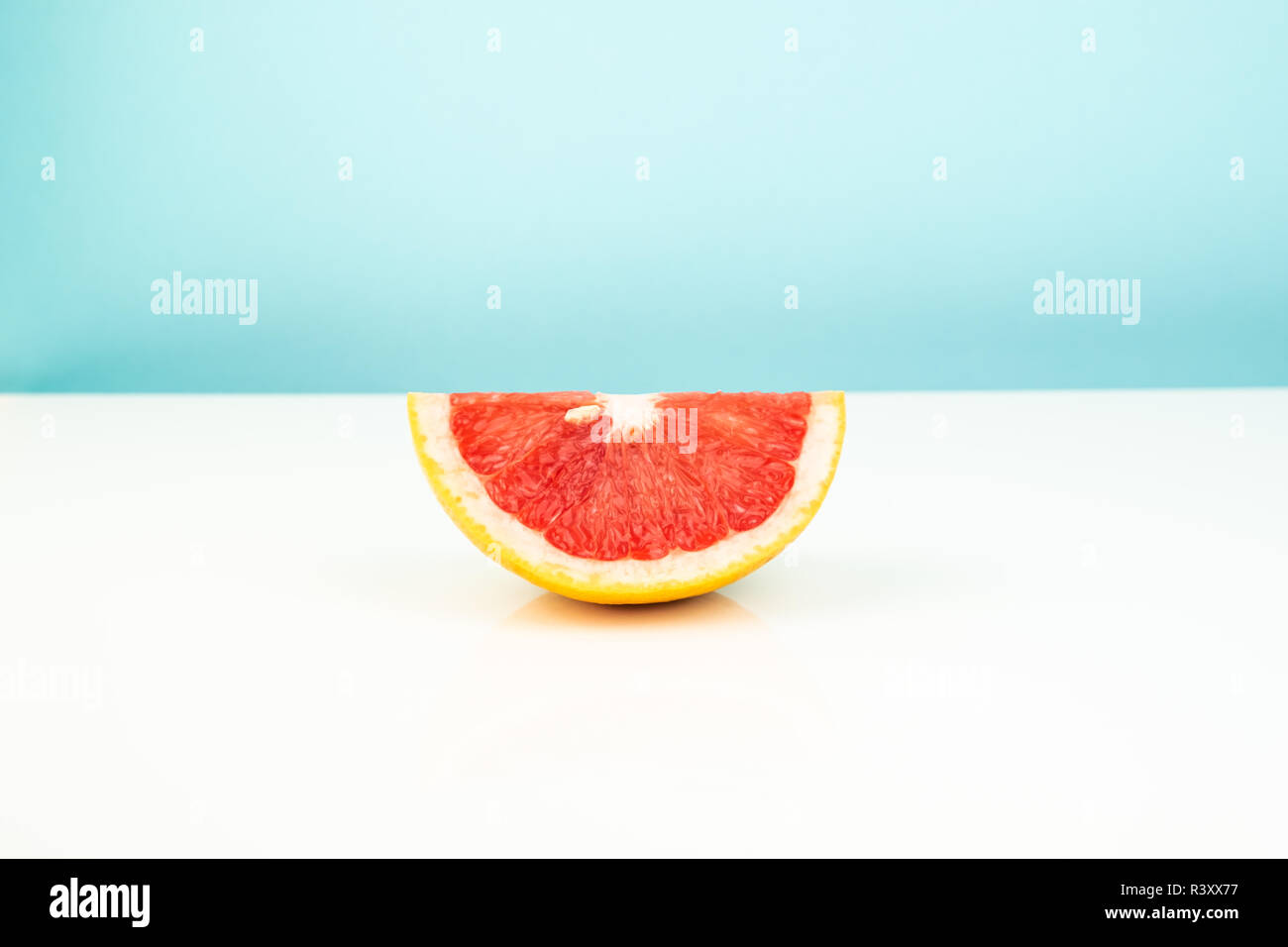 Die Hälfte der Grapefruit auf Weißem und Blauem Hintergrund. Minimalistischer Bild von Slice von Zitrusfrüchten auf spärliche Hell. Stockfoto
