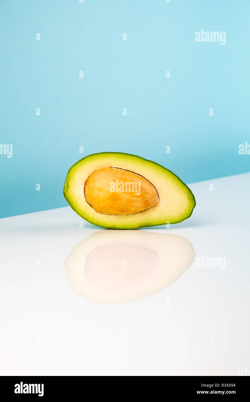 Halbe avocado Frucht auf weißer Tisch. Minimalistischer Bild von Stück Alligator Pear in helles Studio Hintergrund Stockfoto
