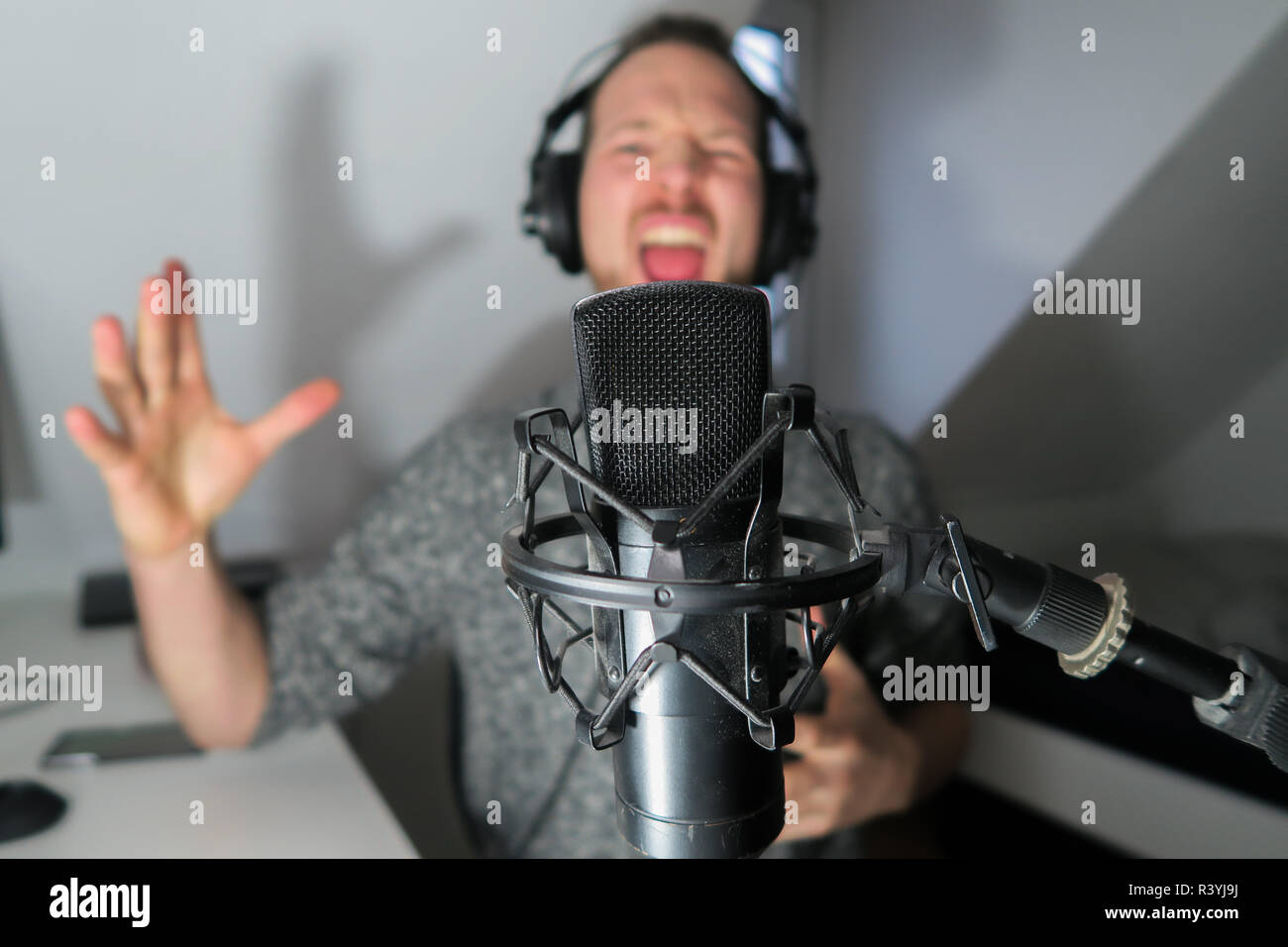 Junge männliche hinter Kondensator Mikrofon radio podcast Host voice recording Stockfoto