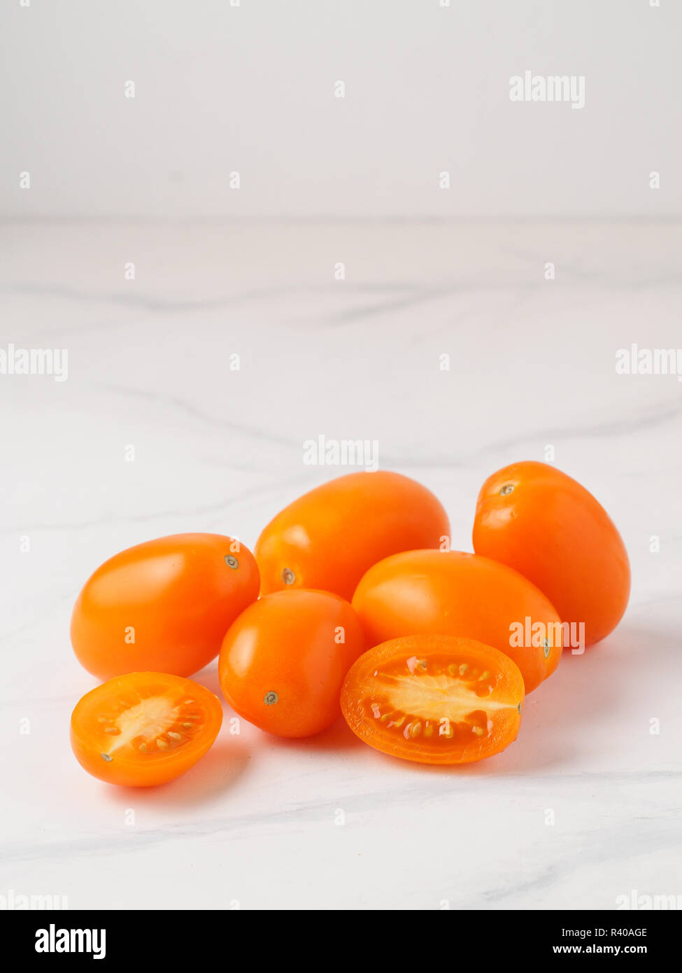 Orange Tomaten auf weißem Marmortisch. Gelb oder Orange Tomaten Heap mit zwei halben Tomate in Scheiben geschnitten. Kopieren Sie Platz für Text Stockfoto