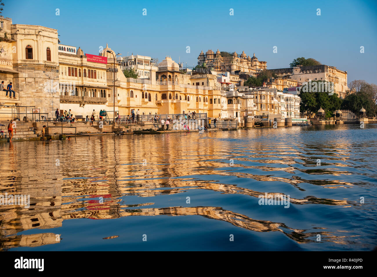 Ein abendlicher Blick Badesee auf dem Ghat oder Bank außerhalb der Bagore-ki-Haveli von goldenen Licht vom See in Udaipur, Indien genommen leuchtet Stockfoto