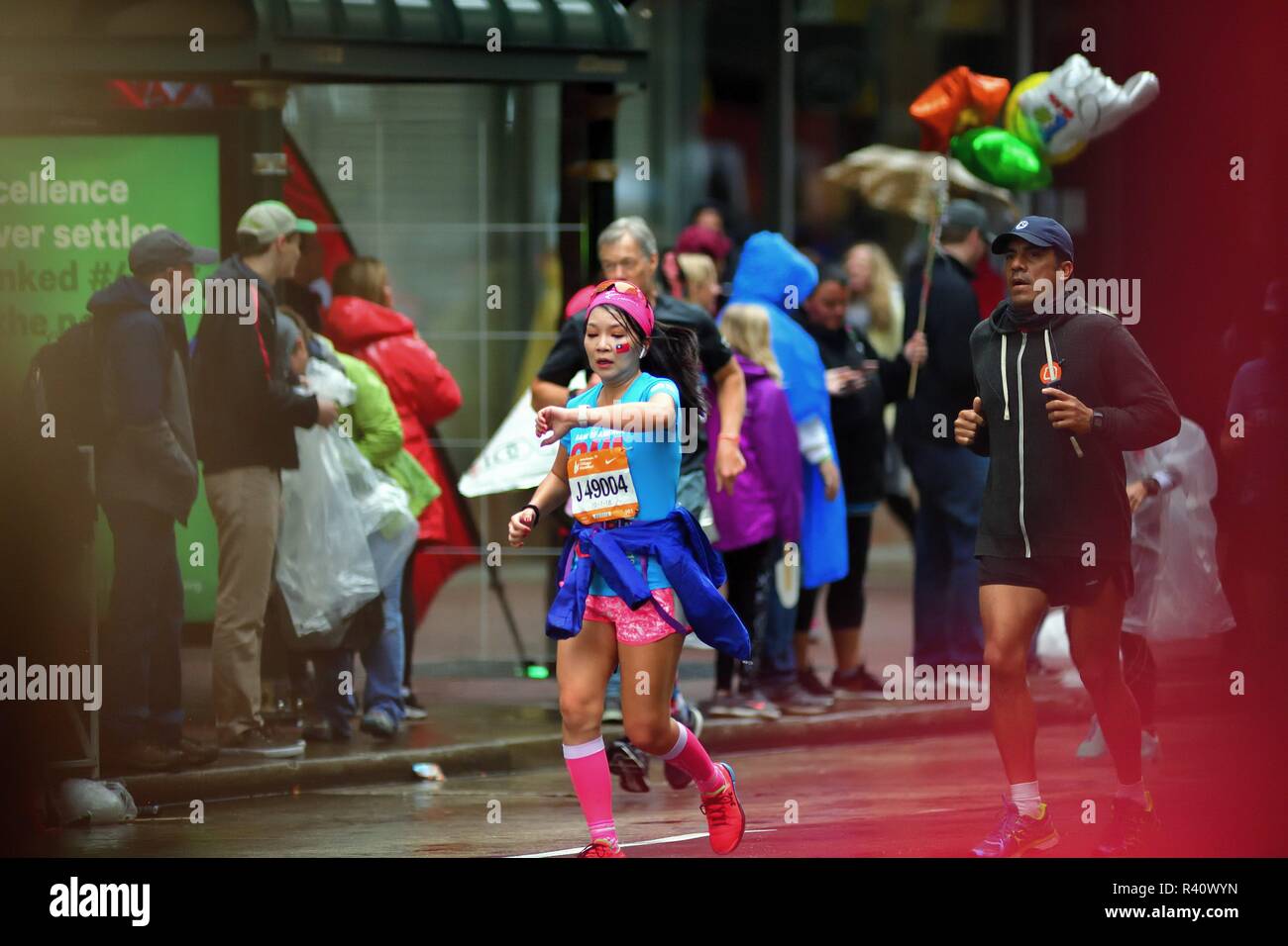 Chicago, Illinois, USA. Eine bunte Teilnehmer, mit einer Flagge von Taiwan pocht auf auf ihrer Wange, überprüft Ihre Zeit während des Chicago Marathon. Stockfoto