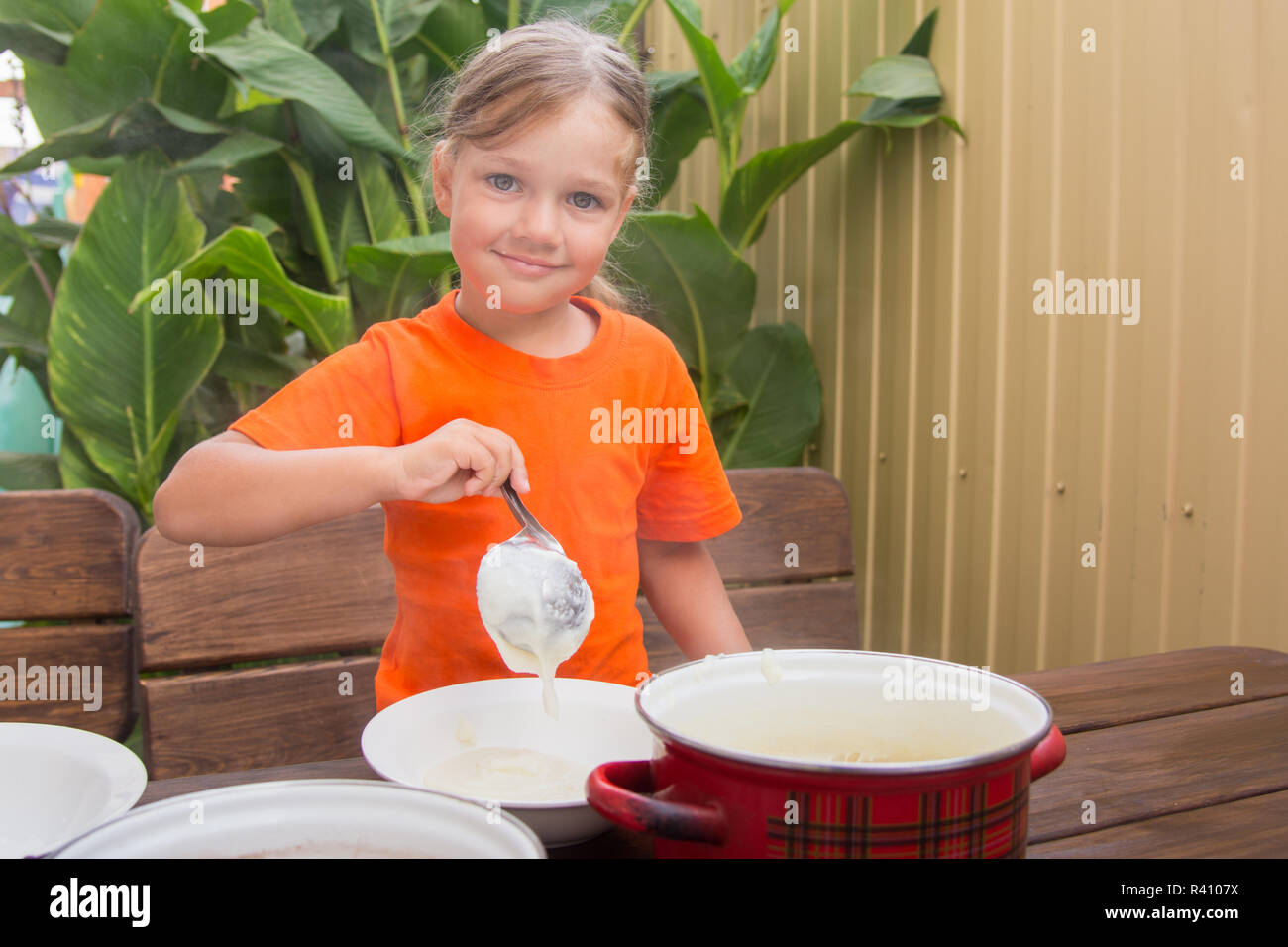 Das Mädchen legt auf Frühstück Brei Stockfoto