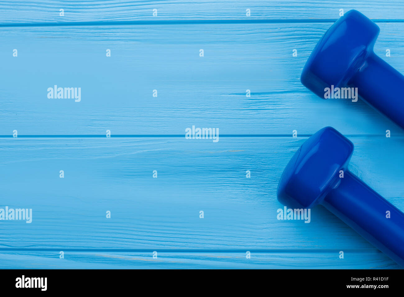 Kurzhanteln auf hölzernen Hintergrund mit kopieren. Zwei hand Gewicht Kurzhanteln auf blauen Brettern mit Text. Ausrüstung für Fitness Übungen. Stockfoto