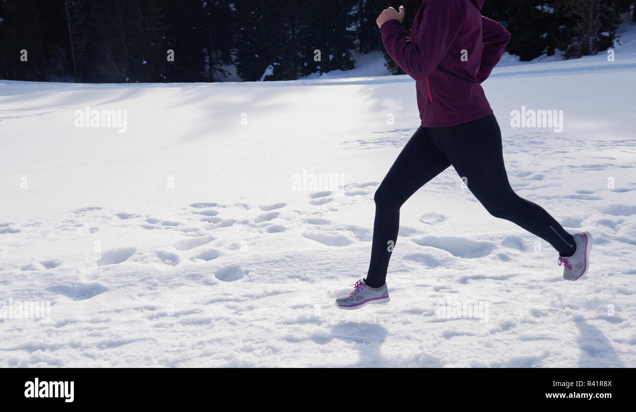 Yougn Frau Joggen im Freien auf Schnee im Wald Stockfoto