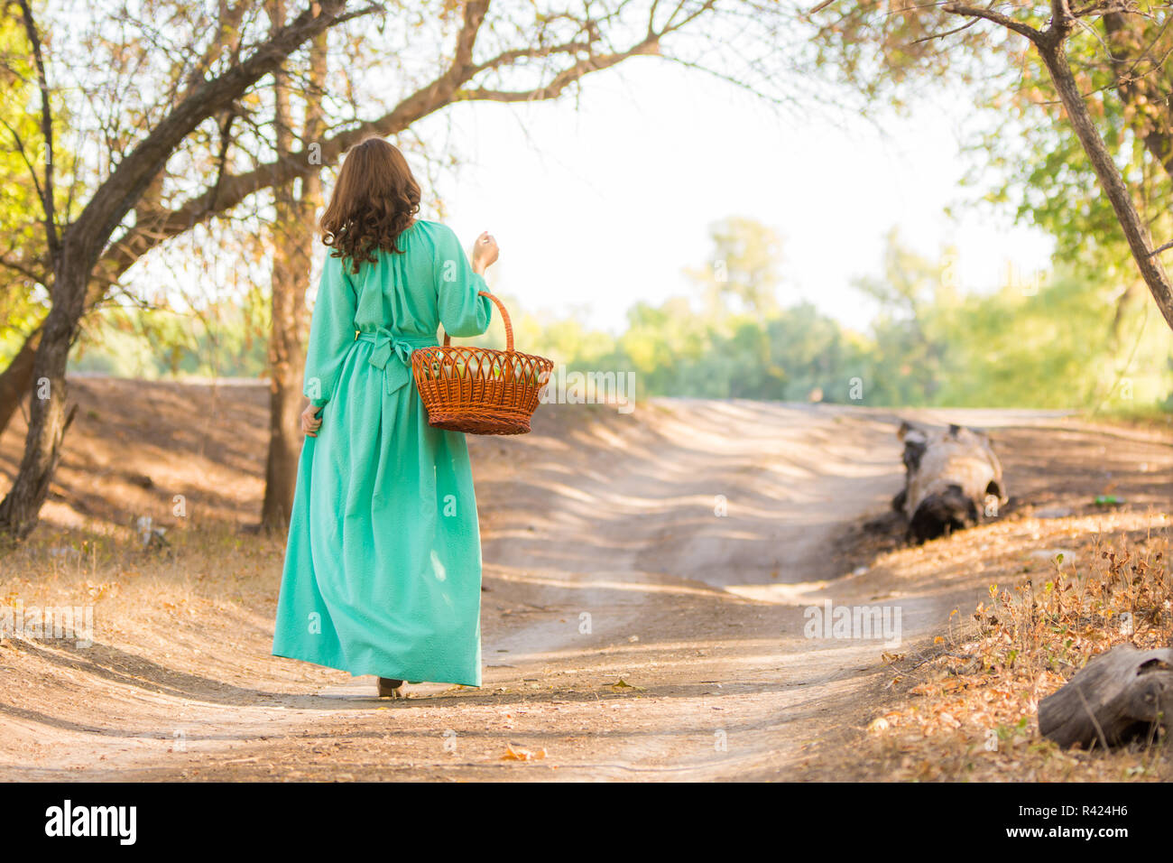 Eine Mädchen in einem langen Kleid mit einem Korb ist auf dem Weg in die Ferne Stockfoto