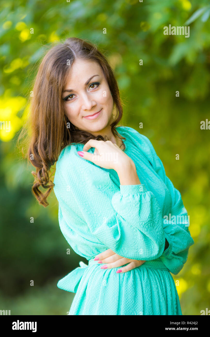 Brustbild eines schönen Mädchens in einem Kleid auf einem Hintergrund von Laub Stockfoto