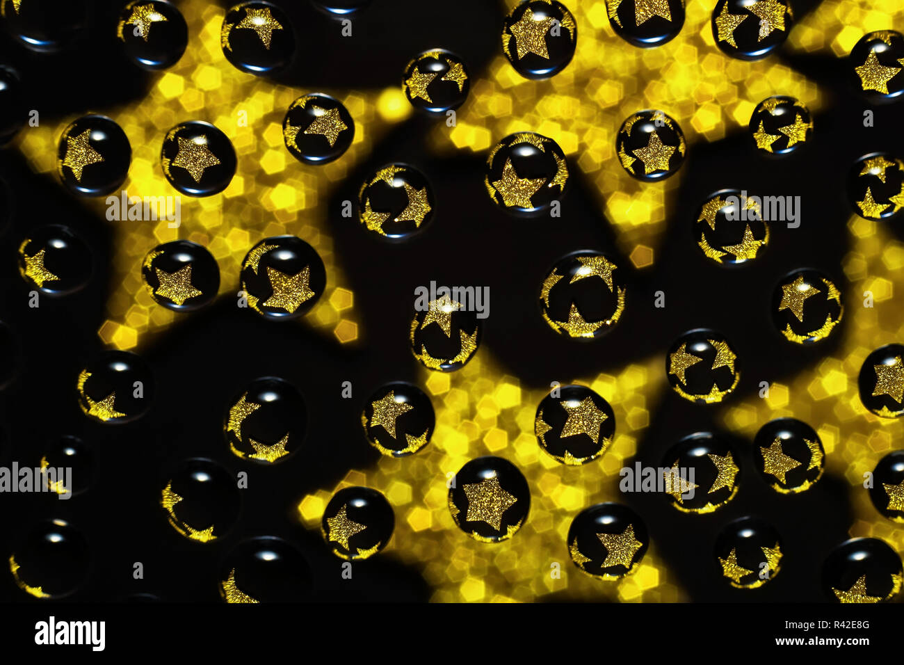 Wassertröpfchen in der Form der schwarzen Kugeln mit Reflexionen von goldenen Sternen Stockfoto