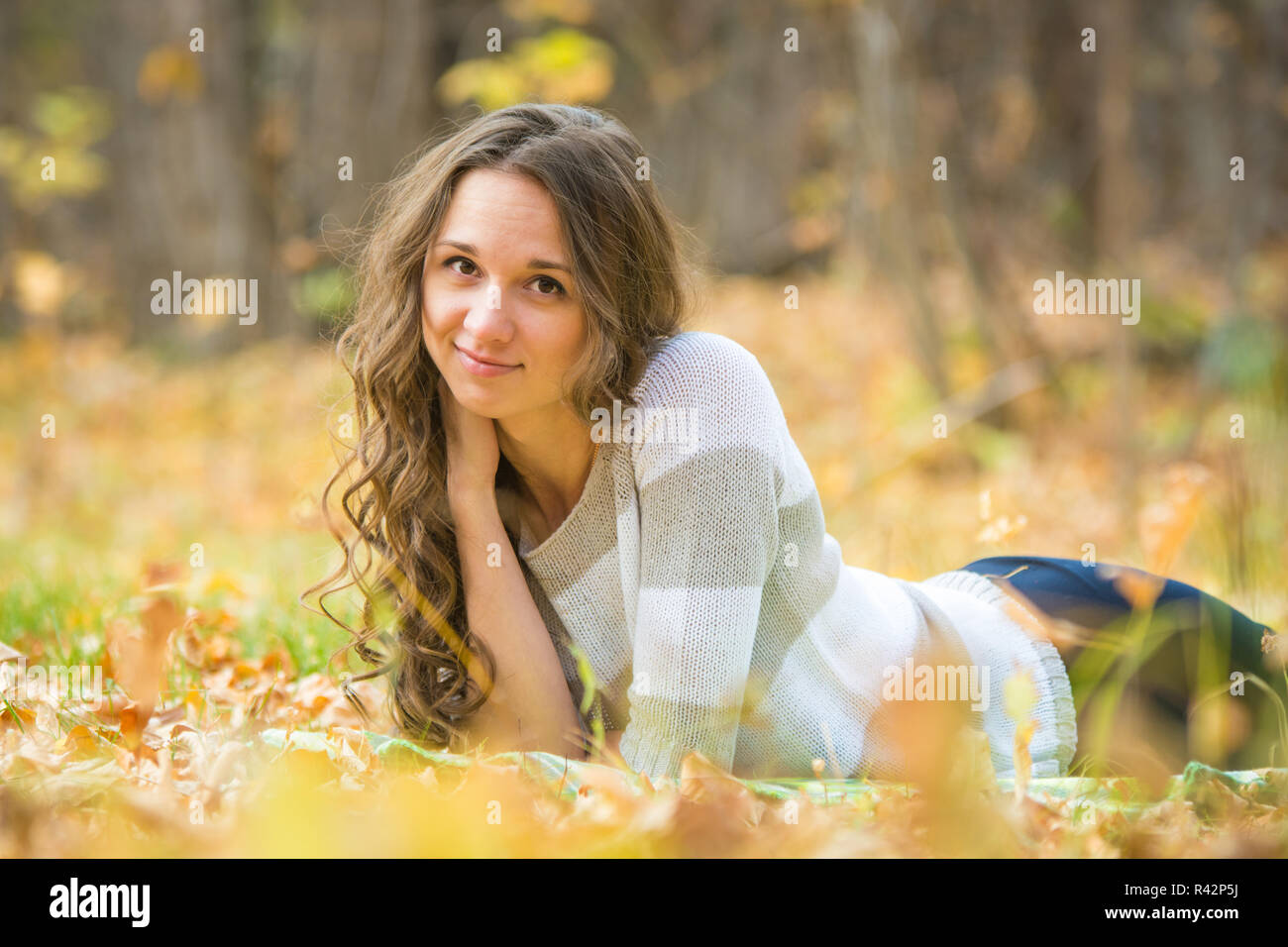 Junges schönes Mädchen liegt auf der Geißel in der gelben Laub Stockfoto