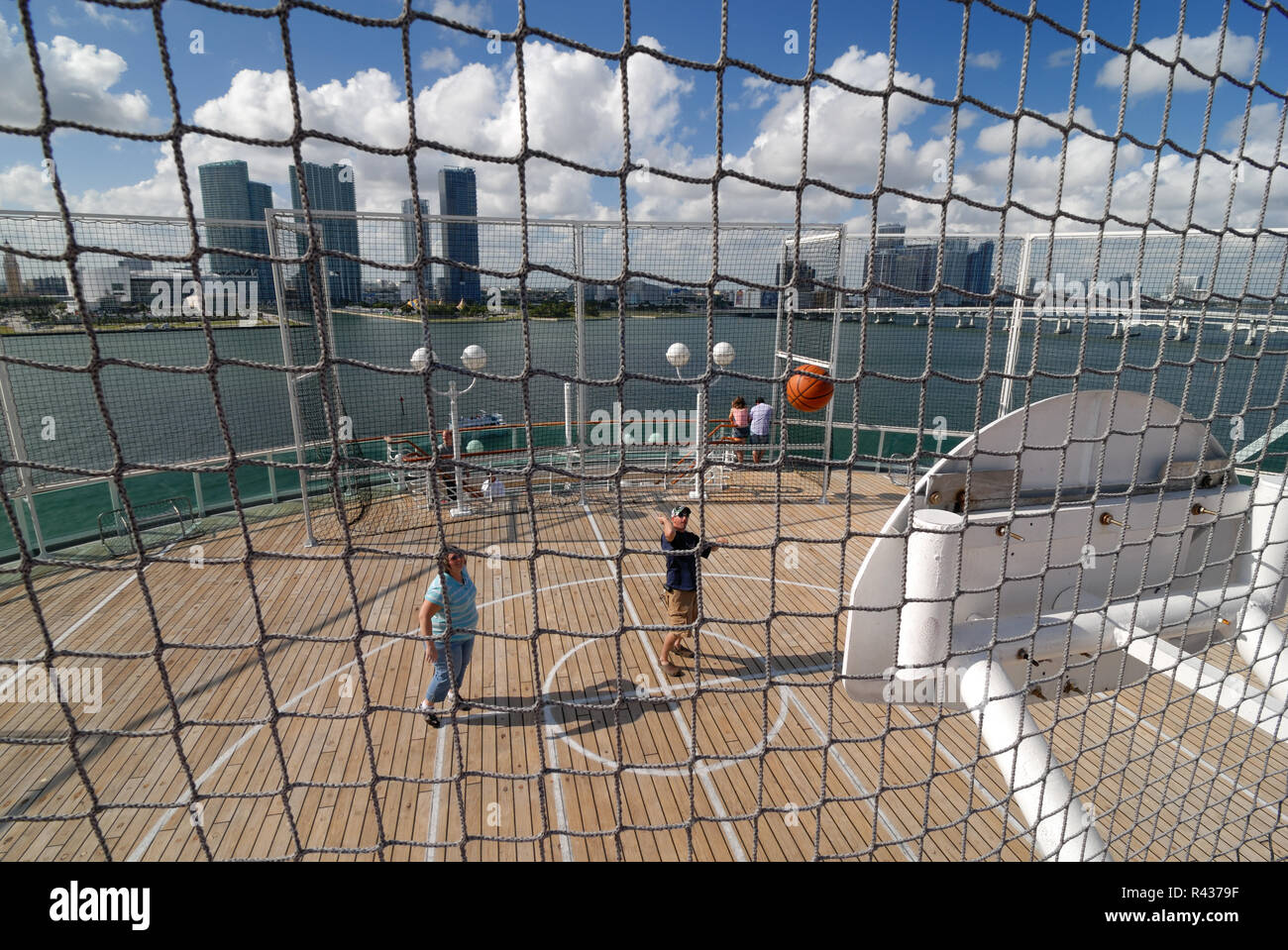 Ein Mann und eine Frau spielen Basketball auf dem Gericht auf der oberen Ebene der Majestät der Meere Kreuzfahrtschiff. Die Skyline von Miami, Florida, können in Th gesehen werden. Stockfoto
