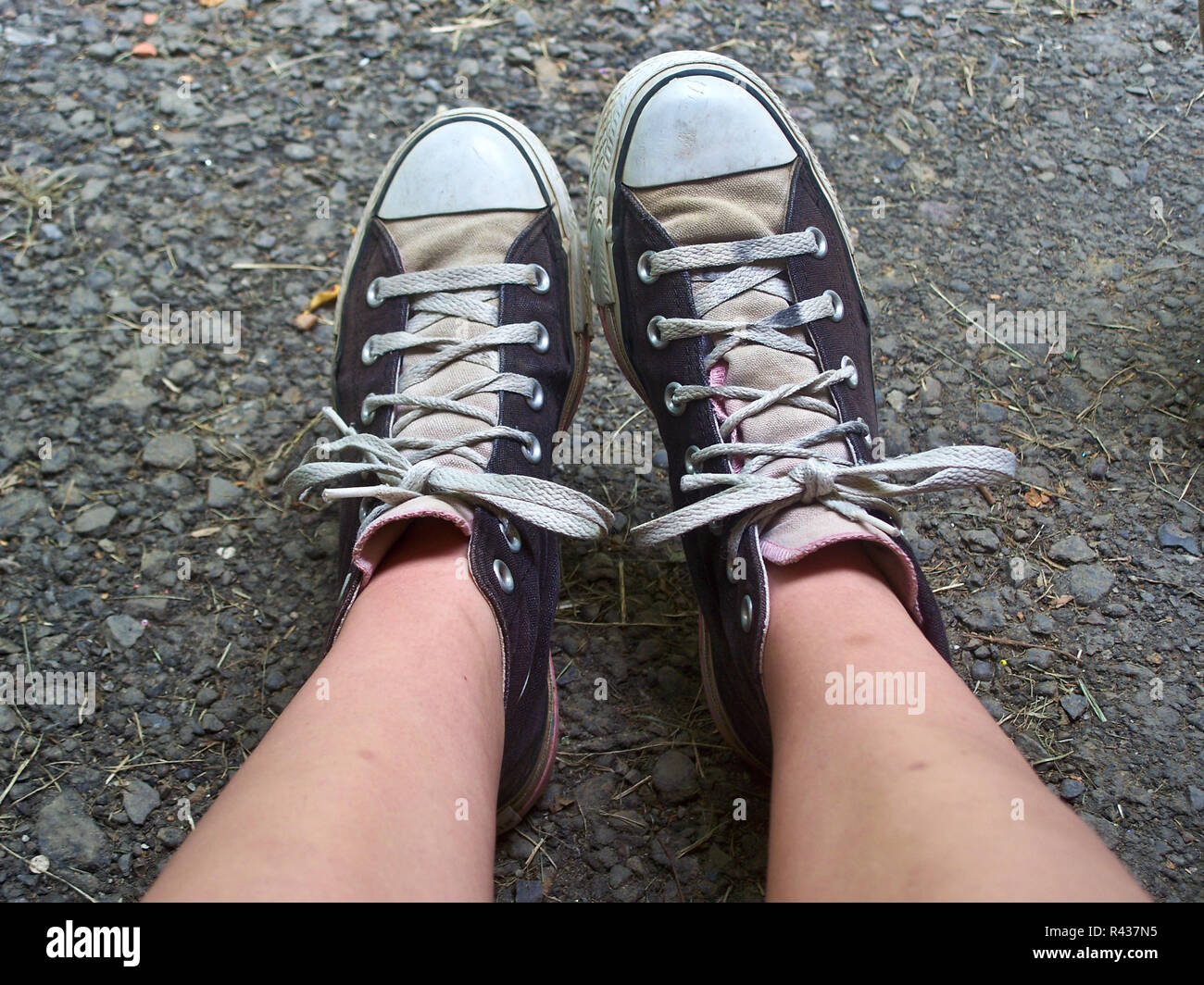 Ein jugendlich Mädchen Füße und Beine, das Tragen von Chuck Taylor High top Converse Tennisschuhe. Stockfoto