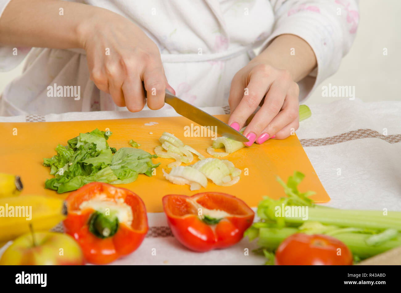 Nahaufnahme von einer weiblichen Hand schneiden Sellerie, liegen rund um Obst und Gemüse Stockfoto