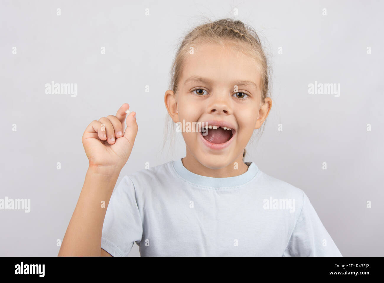 Mädchen hält den Zahn in seiner Hand und Mund offen zeigt ein Loch zwischen den Zähnen Stockfoto