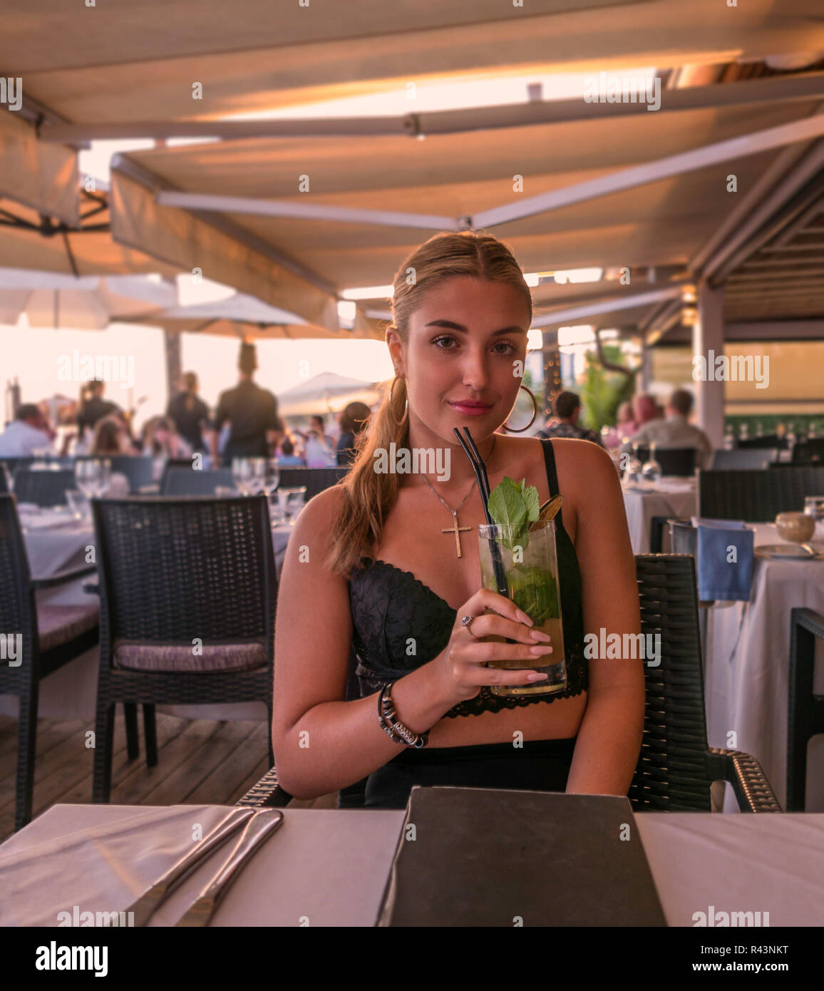 Eine junge Frau trinkt einen Cocktail in einem Restaurant in Marbella, Spanien. Stockfoto