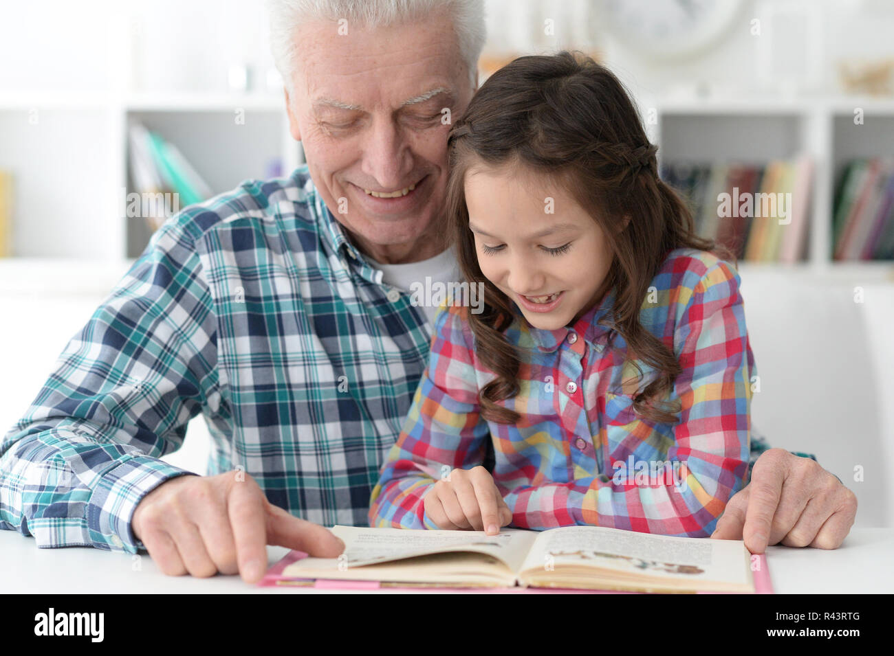 Kleines nettes Mädchen mit Großvater lesen Buch Stockfoto