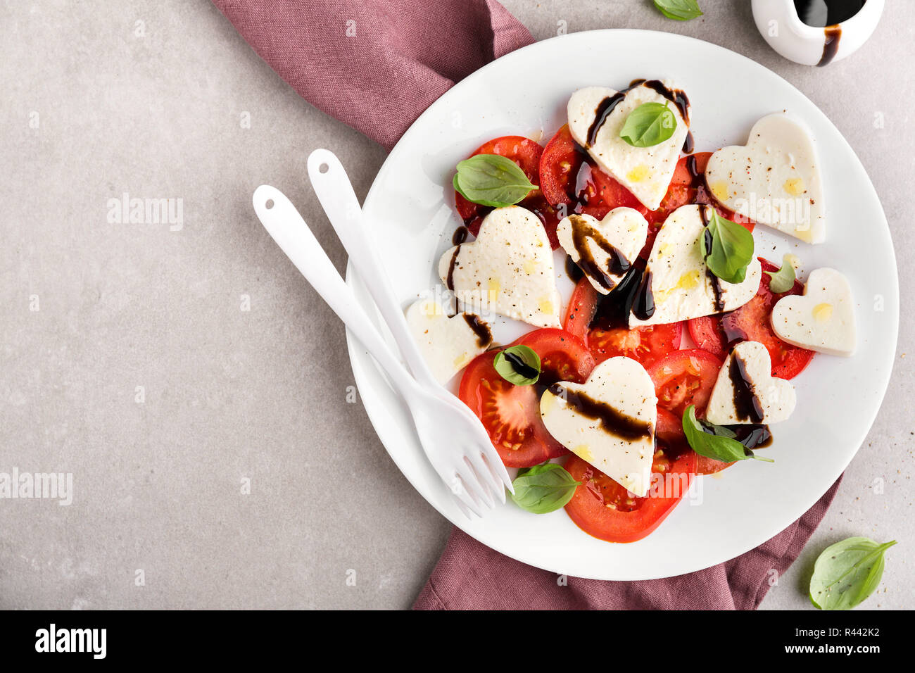 Valentinstag Salat. Klassische italienische Caprese Salat mit Herz gebildet, Mozzarella, Basilikum, Balsamico und Tomaten auf dem Teller serviert. Oben betrachten. Kopieren spa Stockfoto