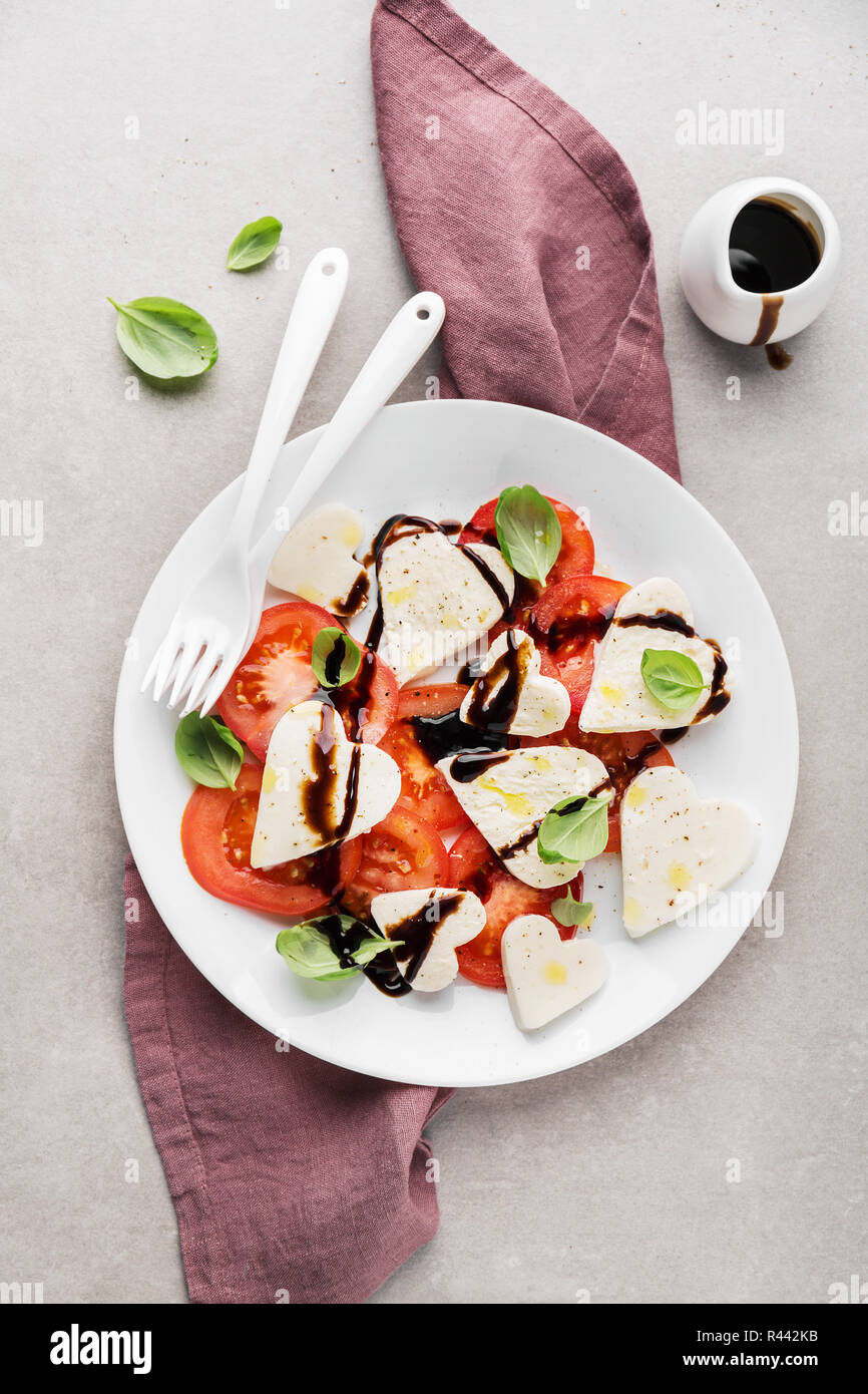 Valentinstag Salat. Klassische italienische Caprese Salat mit Herz gebildet, Mozzarella, Basilikum, Balsamico und Tomaten auf dem Teller serviert. Oben betrachten. Kopieren spa Stockfoto