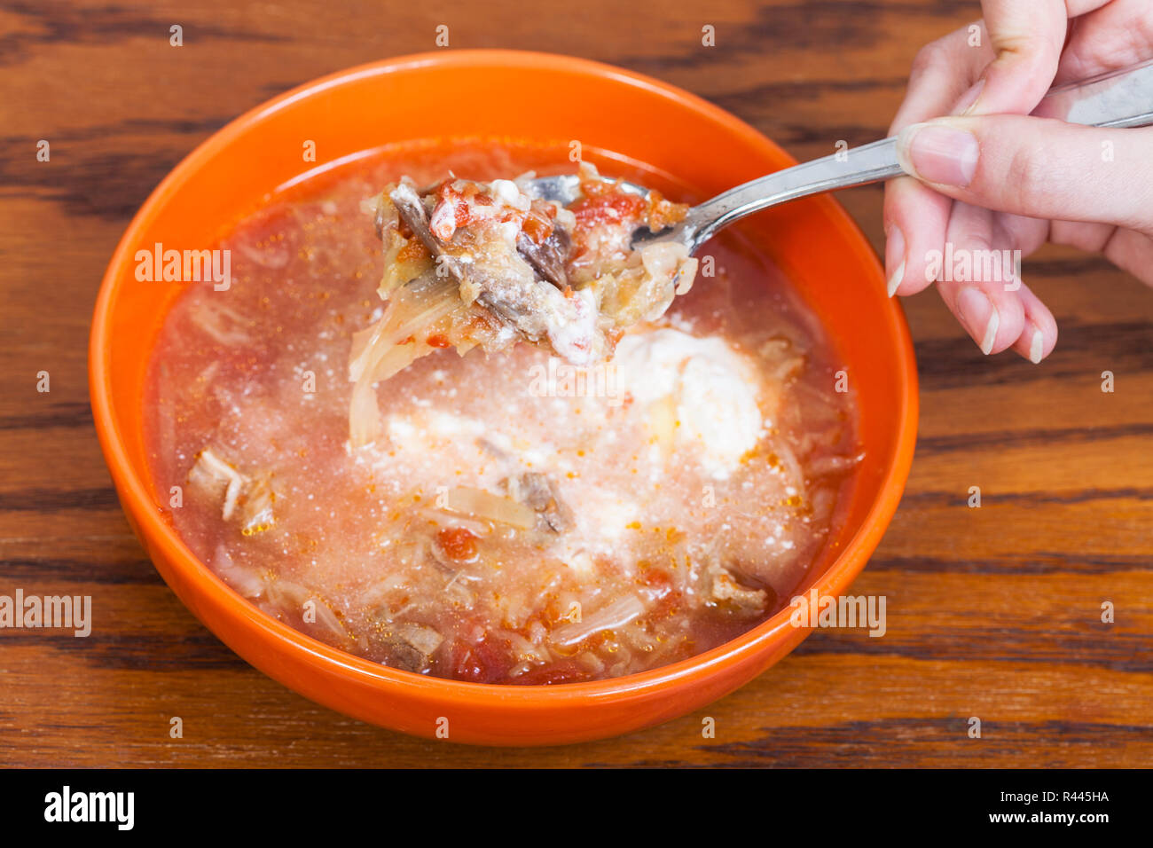 Löffel mit Kohl Suppe in der Hand über Keramik Schüssel Stockfoto