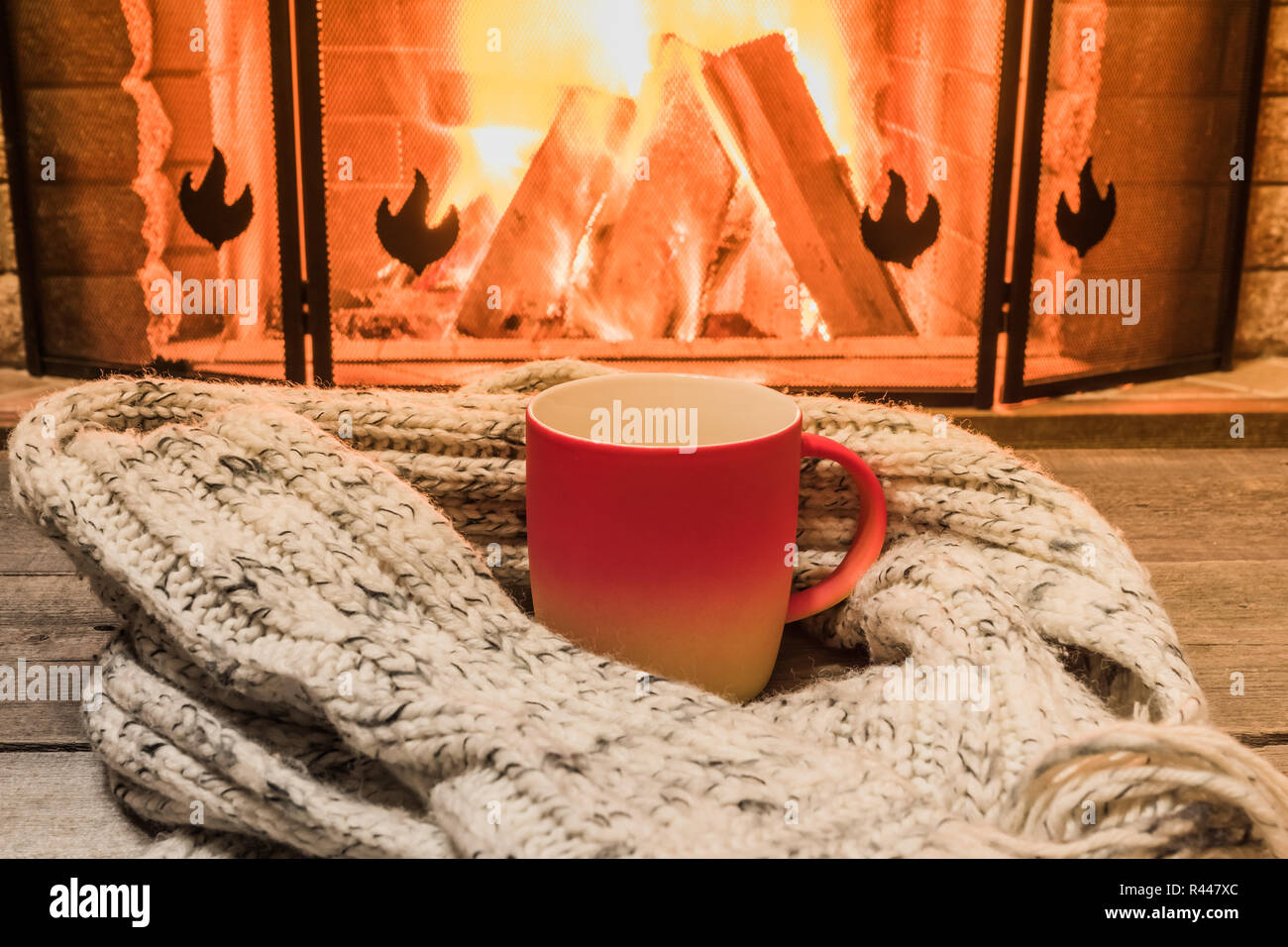 Rot Tasse mit heißem Tee und gemütlich warmen Schal in der Nähe von Kamin, im Landhaus, winter Urlaub, horizontal. Stockfoto