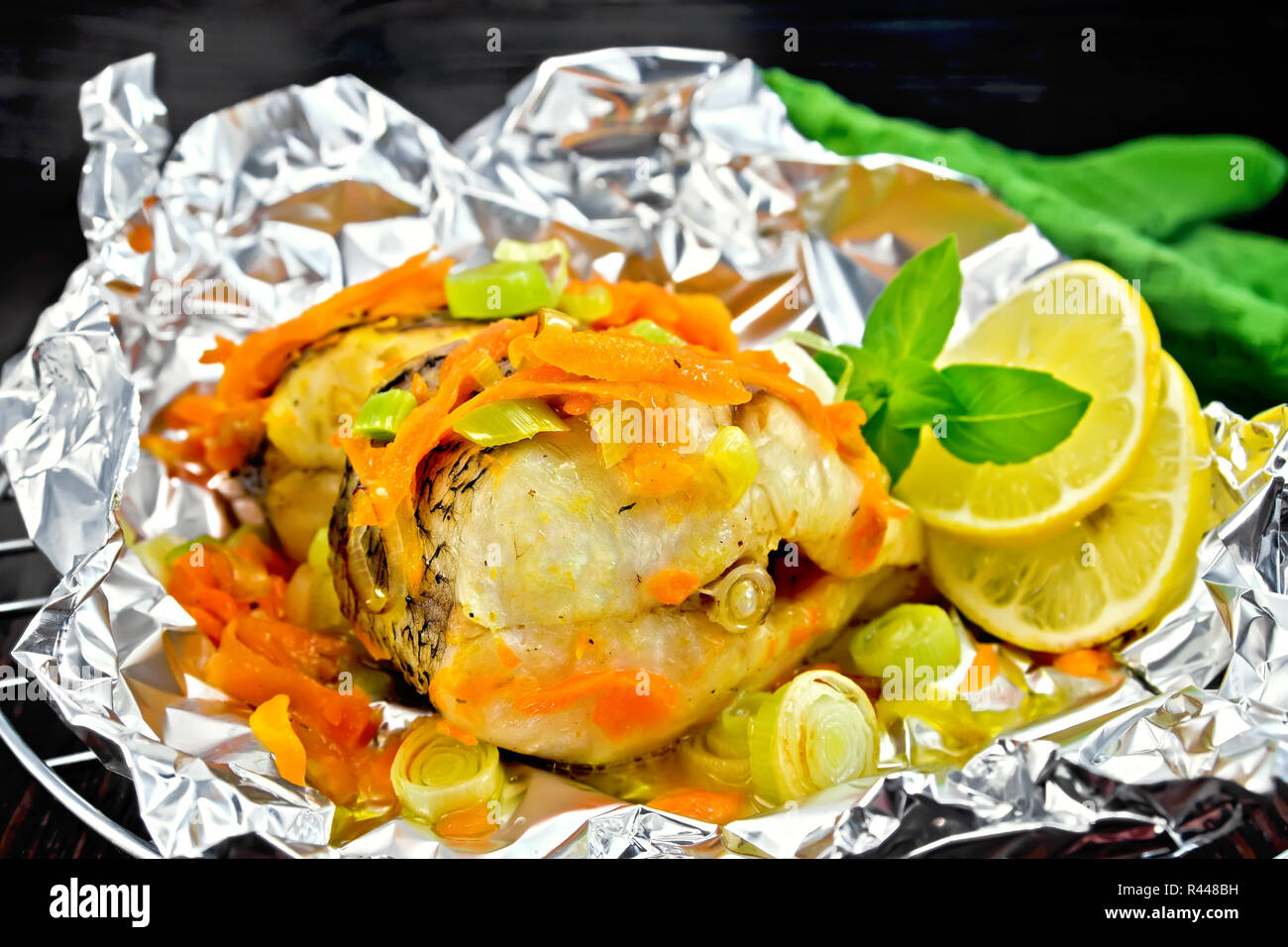 Hecht mit Karotten und Zwiebeln in Folie auf dunklen Kammer Stockfoto