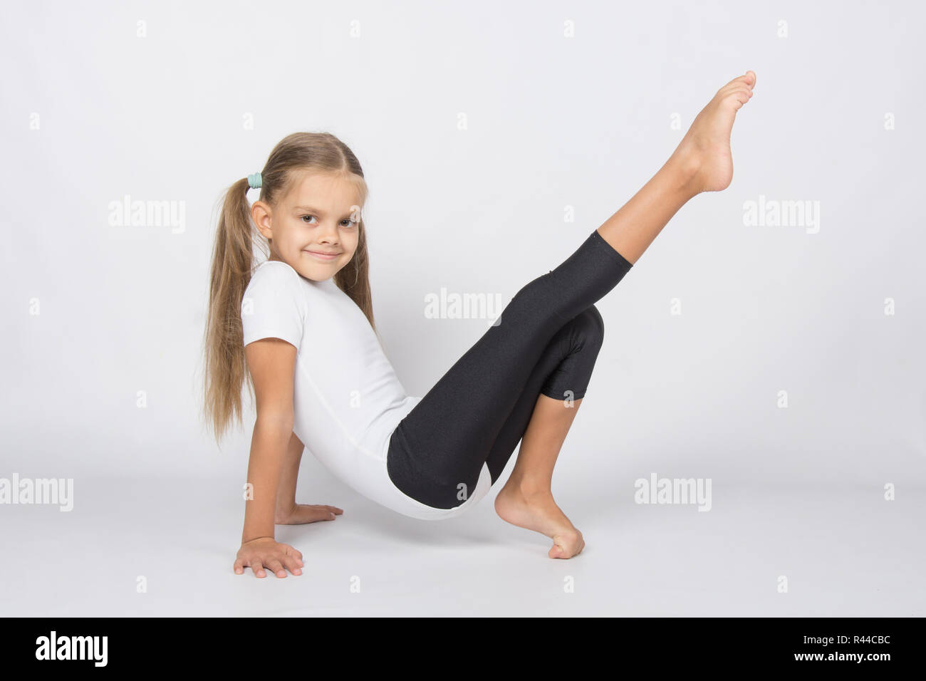 Ein aufstrebender Turnerin zieht sein rechte Bein ruht auf den Händen und Fingern des linken Beines Stockfoto