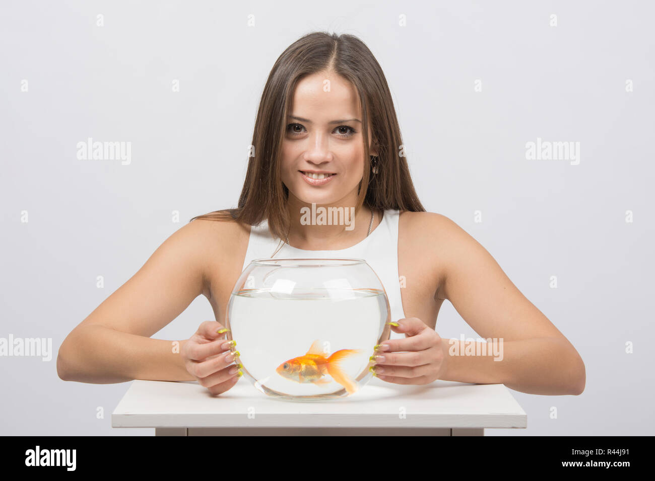 Schönes Mädchen umarmt ein Aquarium mit Goldfischen Stockfoto